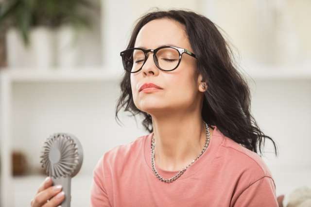 A woman cools off with a handheld fan